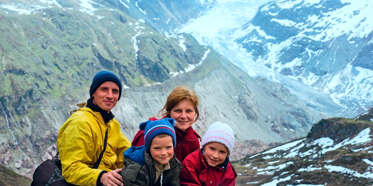 Urlaub mit Kindern in den Alpen - Familie vor Bergmassiv